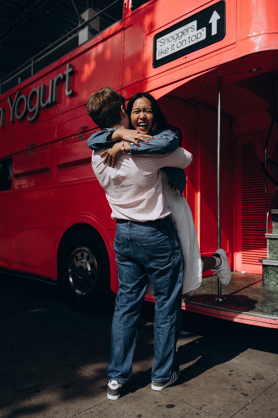 Couple hugging beside a red London bus in central London