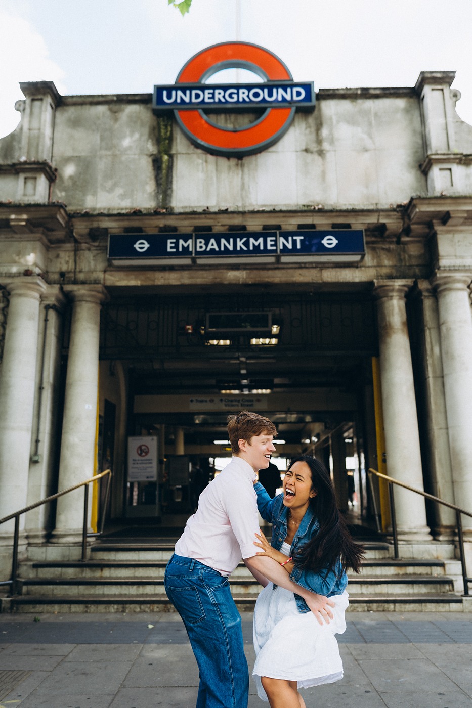 Couple in front of the Embankment Underground roundel