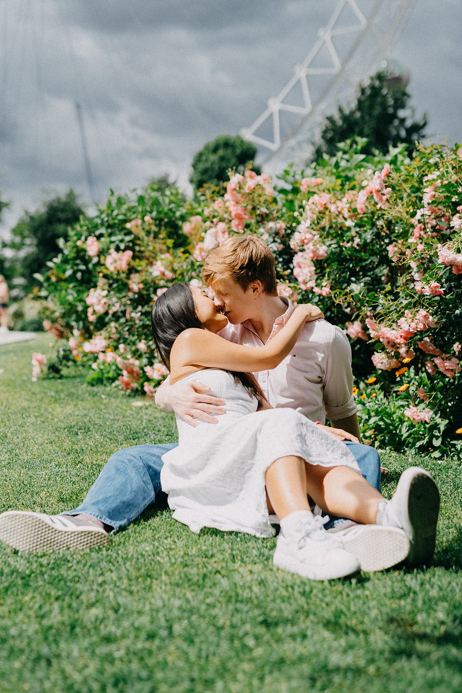Couple sitting on the grass beside a rose bed at the end of the shoot