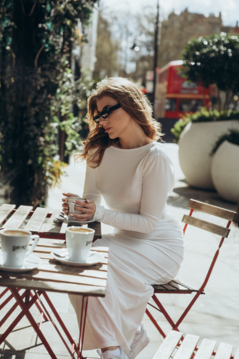 Photography session: woman in a white dress enjoying coffee at a London café