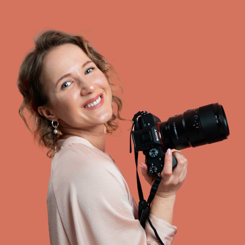 Elena from Cup of Green, smiling and holding her camera