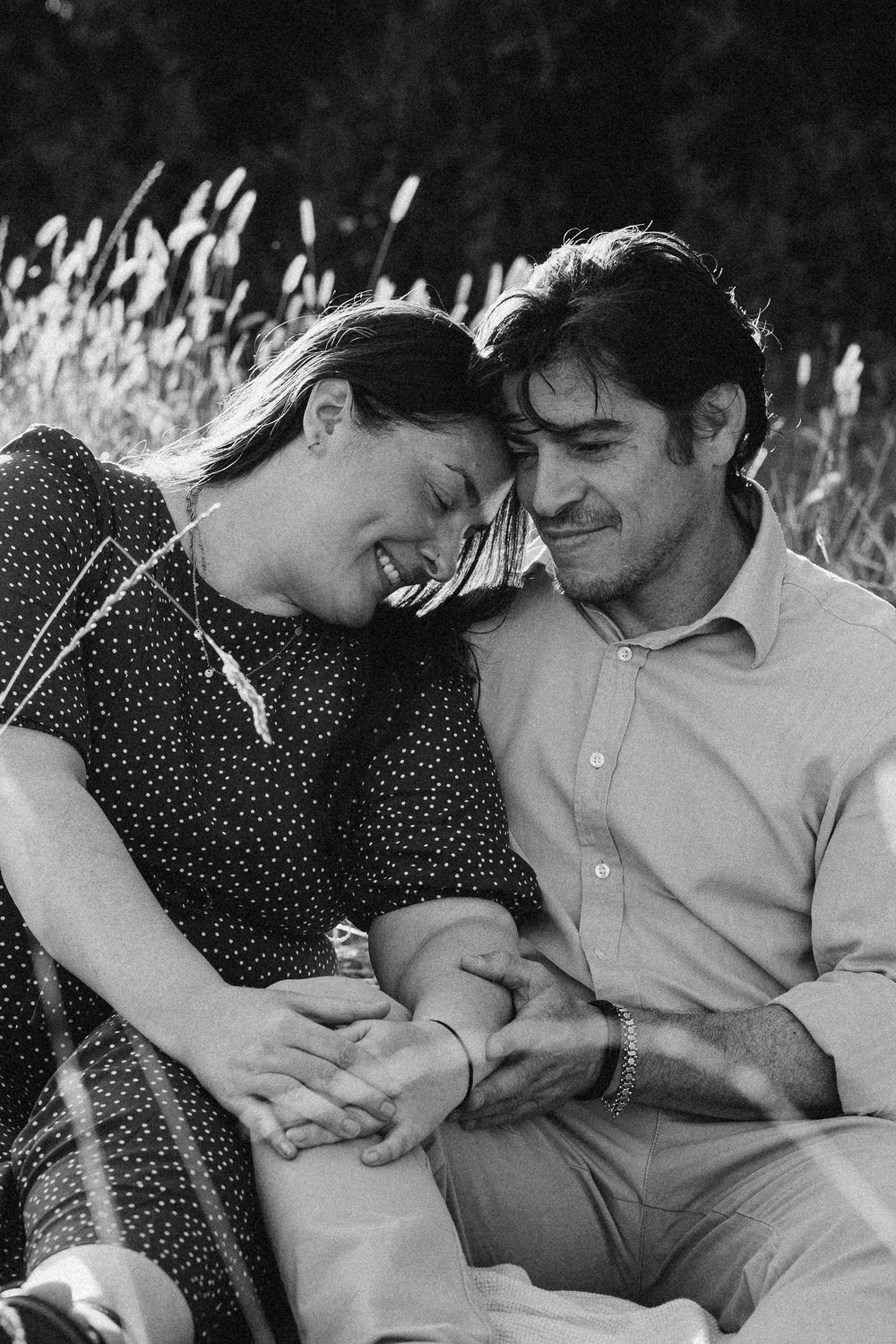 Black and white portrait of a couple laughing together in a Surrey field