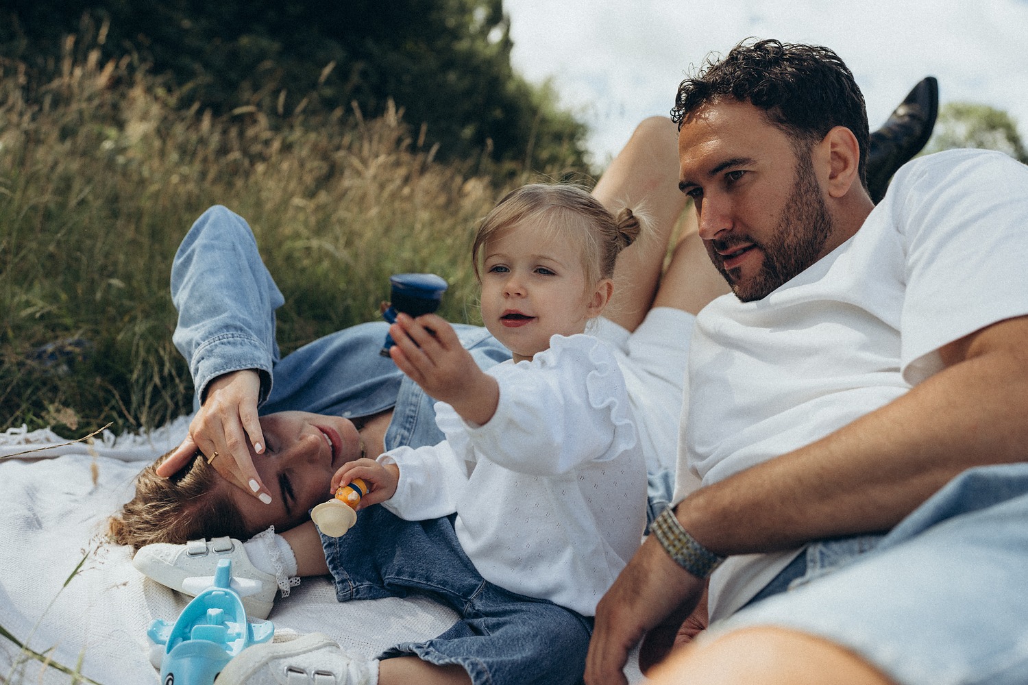 Family relaxing on a picnic blanket in the long grass