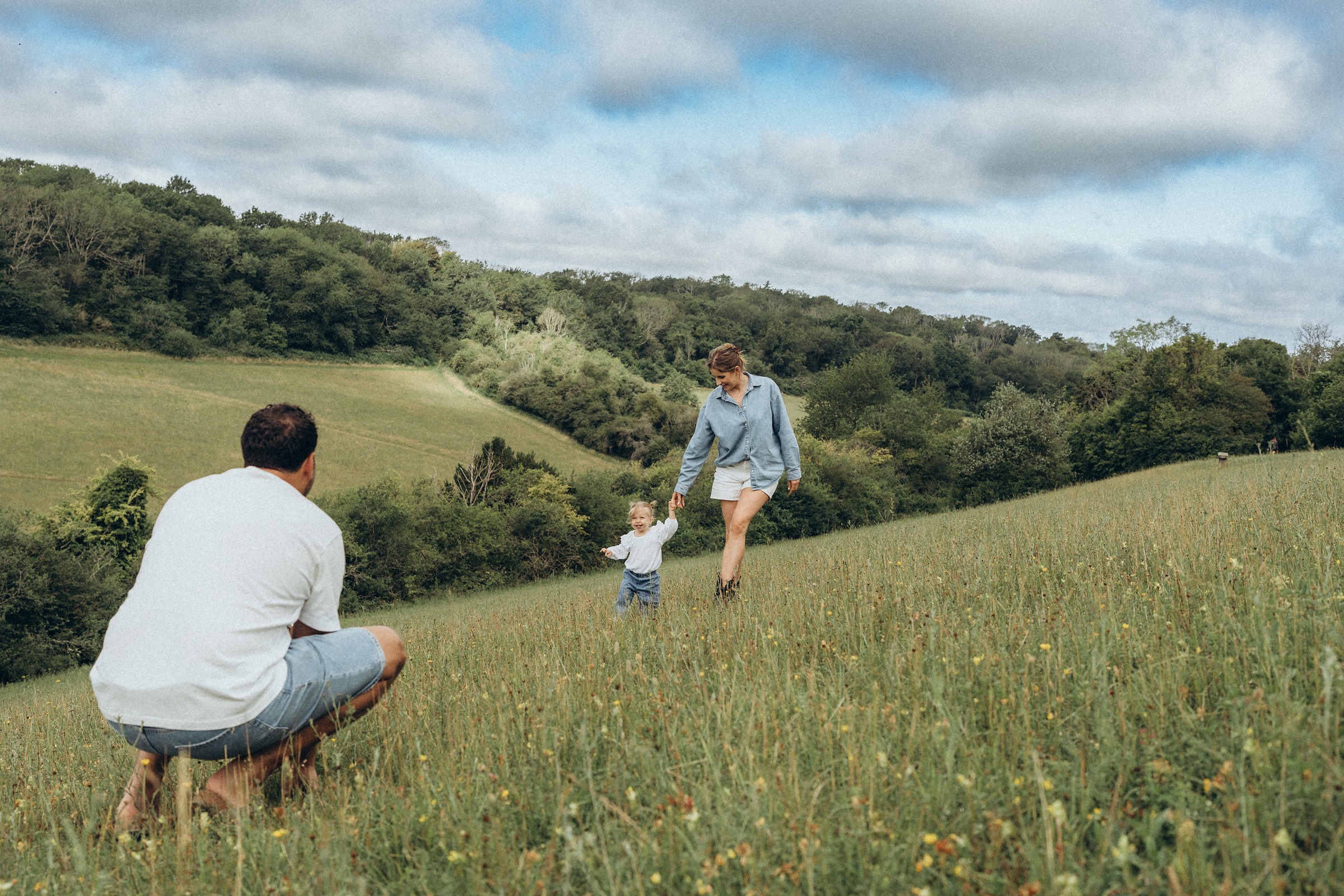 Toddler running up a hillside path towards her father with the hills behind