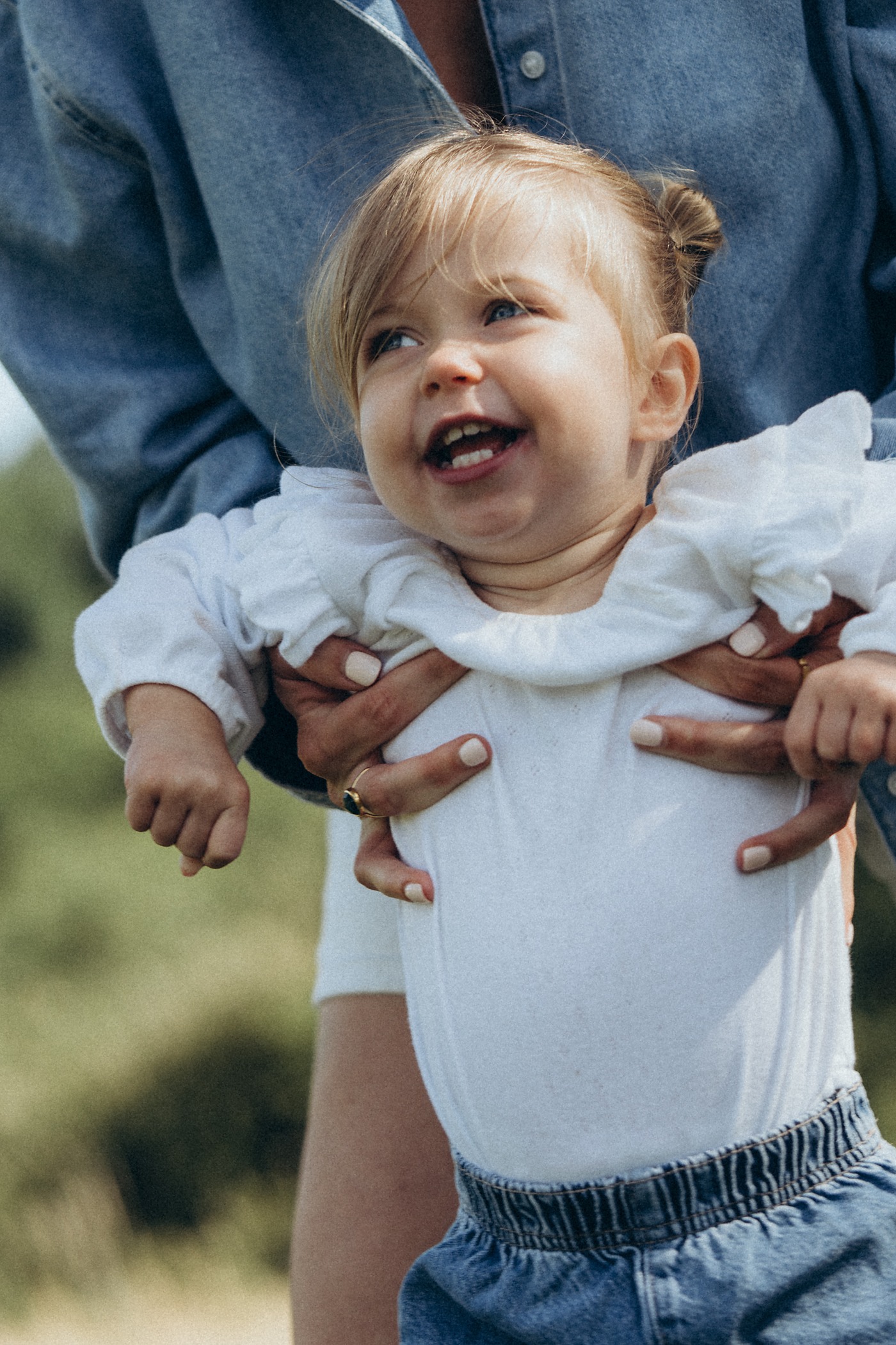 Toddler giggling as she is held up by her mum