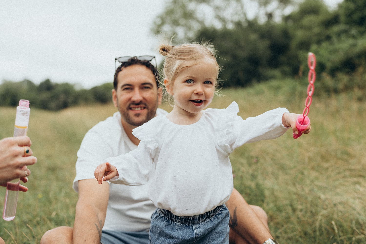 Dad and toddler blowing bubbles in a summer meadow
