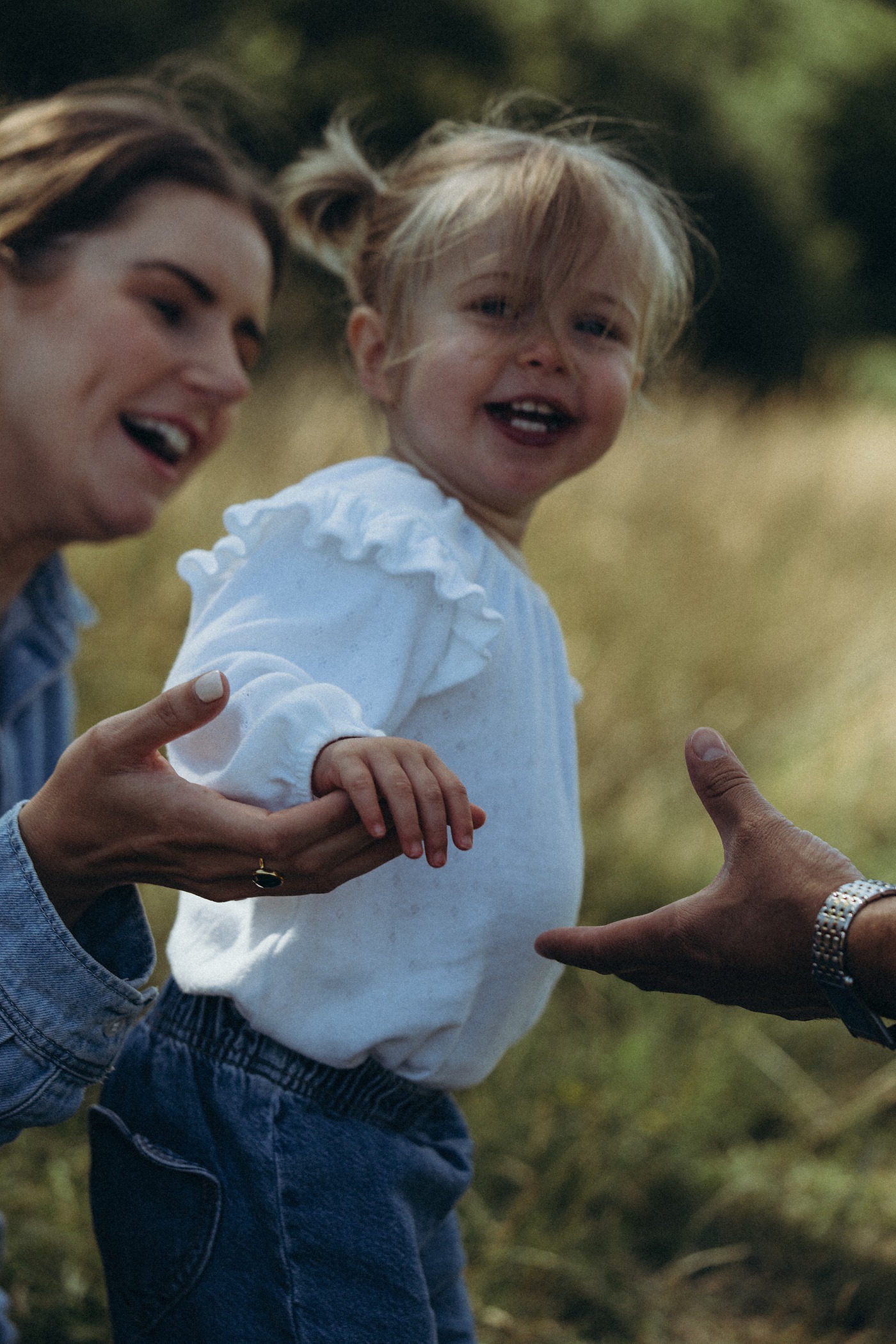Mum and toddler laughing together in the long grass