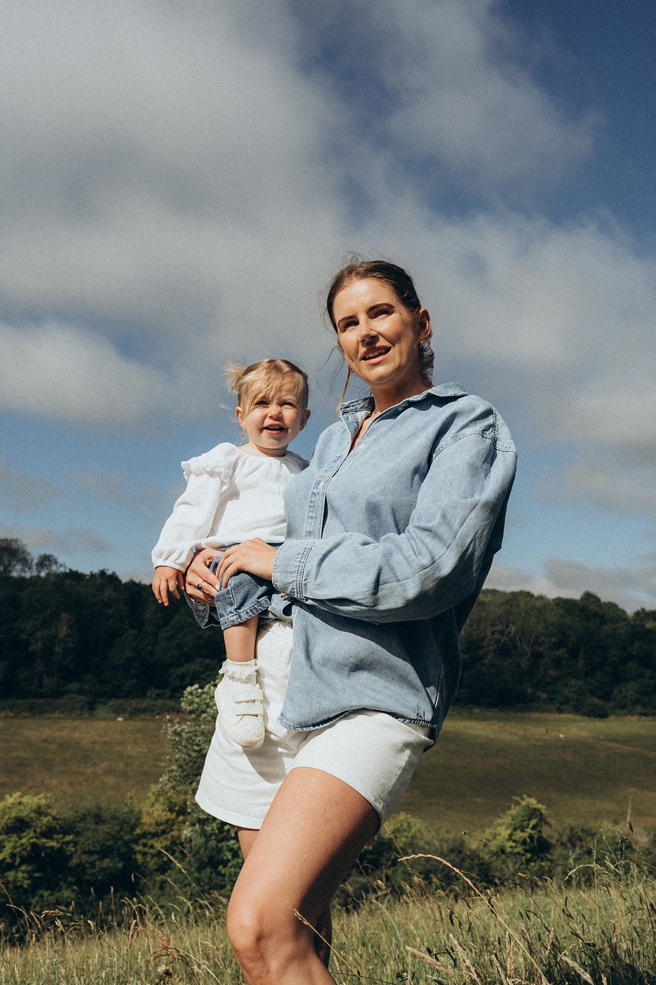 Mother holding her daughter against a big summer sky