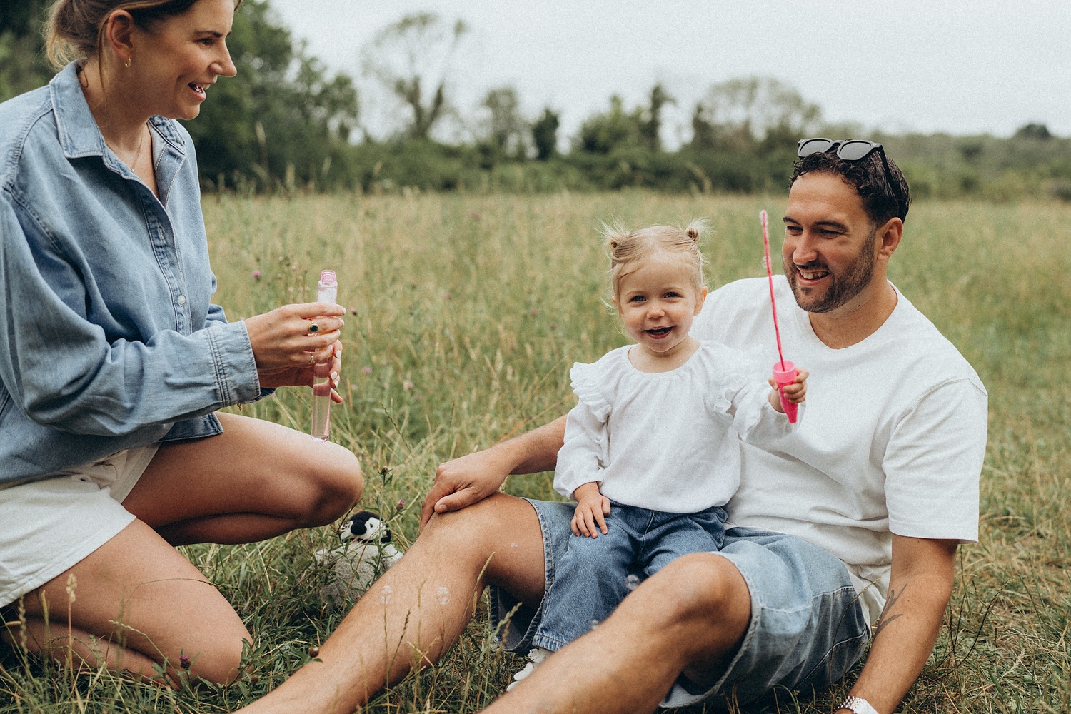 Family blowing bubbles together in a summer meadow