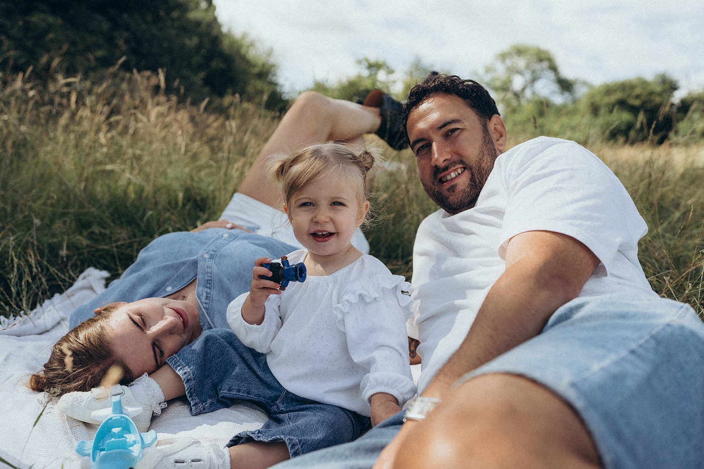 Family lying on a picnic blanket in the long grass