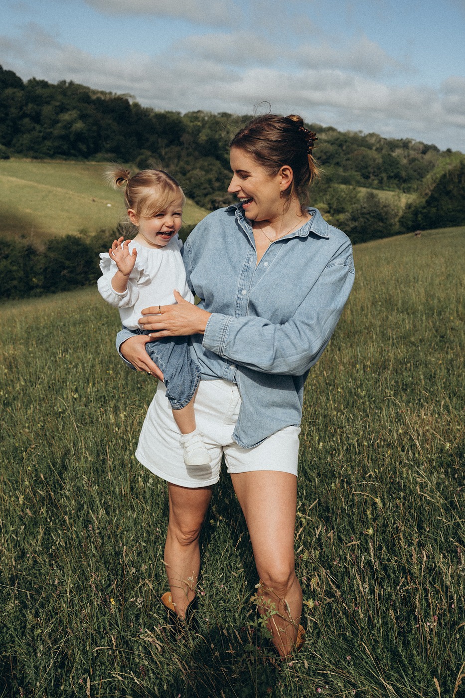 Mother holding her toddler in a meadow of tall grass