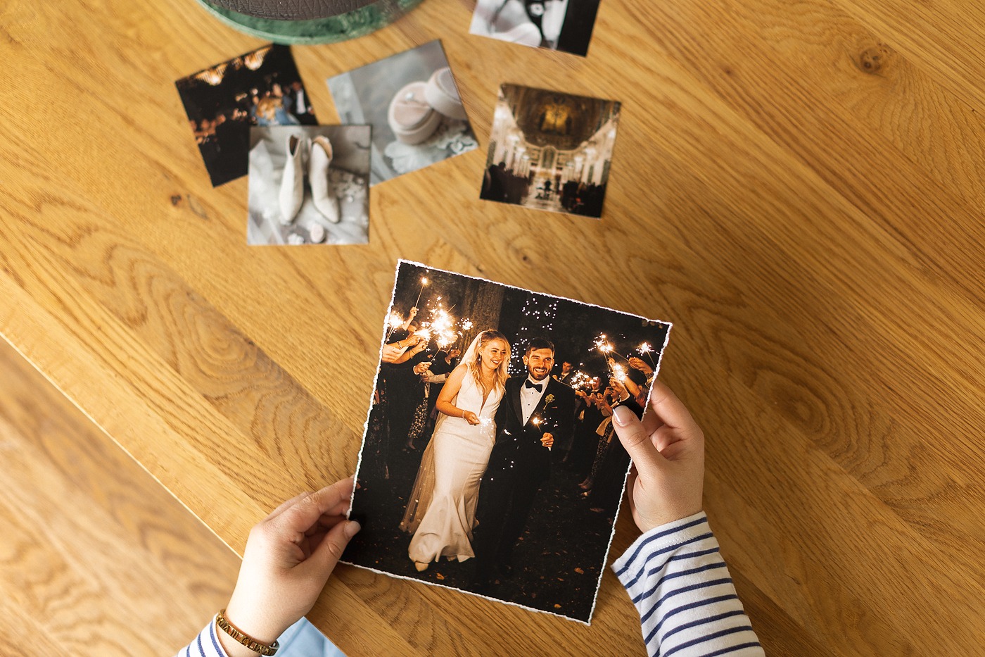 Hands holding a fine art print above more prints spread across a wooden floor