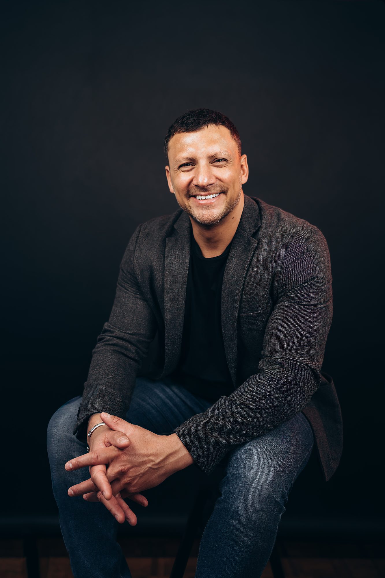 Natural business headshot of a smiling man against a dark backdrop, Surrey