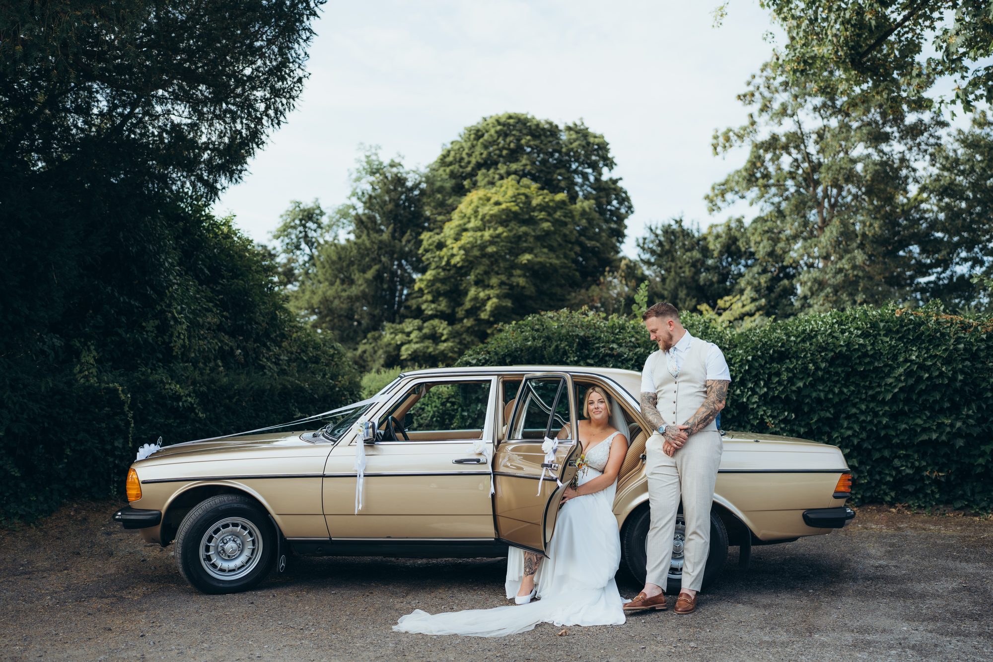 Newlyweds beside a vintage car after their wedding