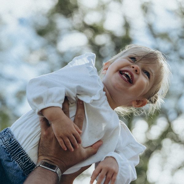 Little girl laughing as she is lifted towards the sky