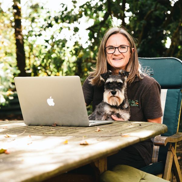 Business owner with her dog and laptop at a woodland table