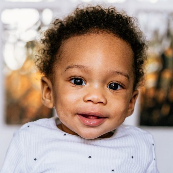 Toddler with curly hair smiling straight at the camera