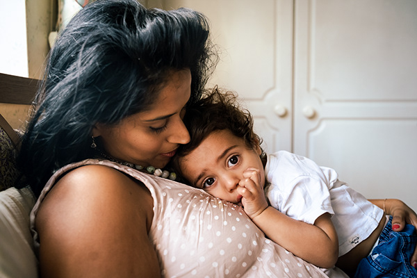 Mother cuddling her toddler on the bed during an at-home session in Surrey