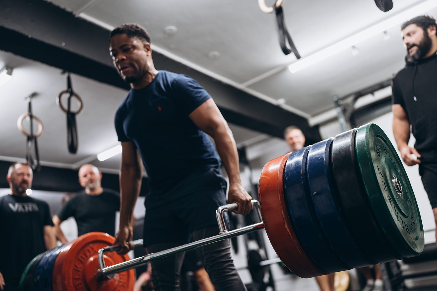 Member lifting a heavily loaded trap bar while his teammates watch