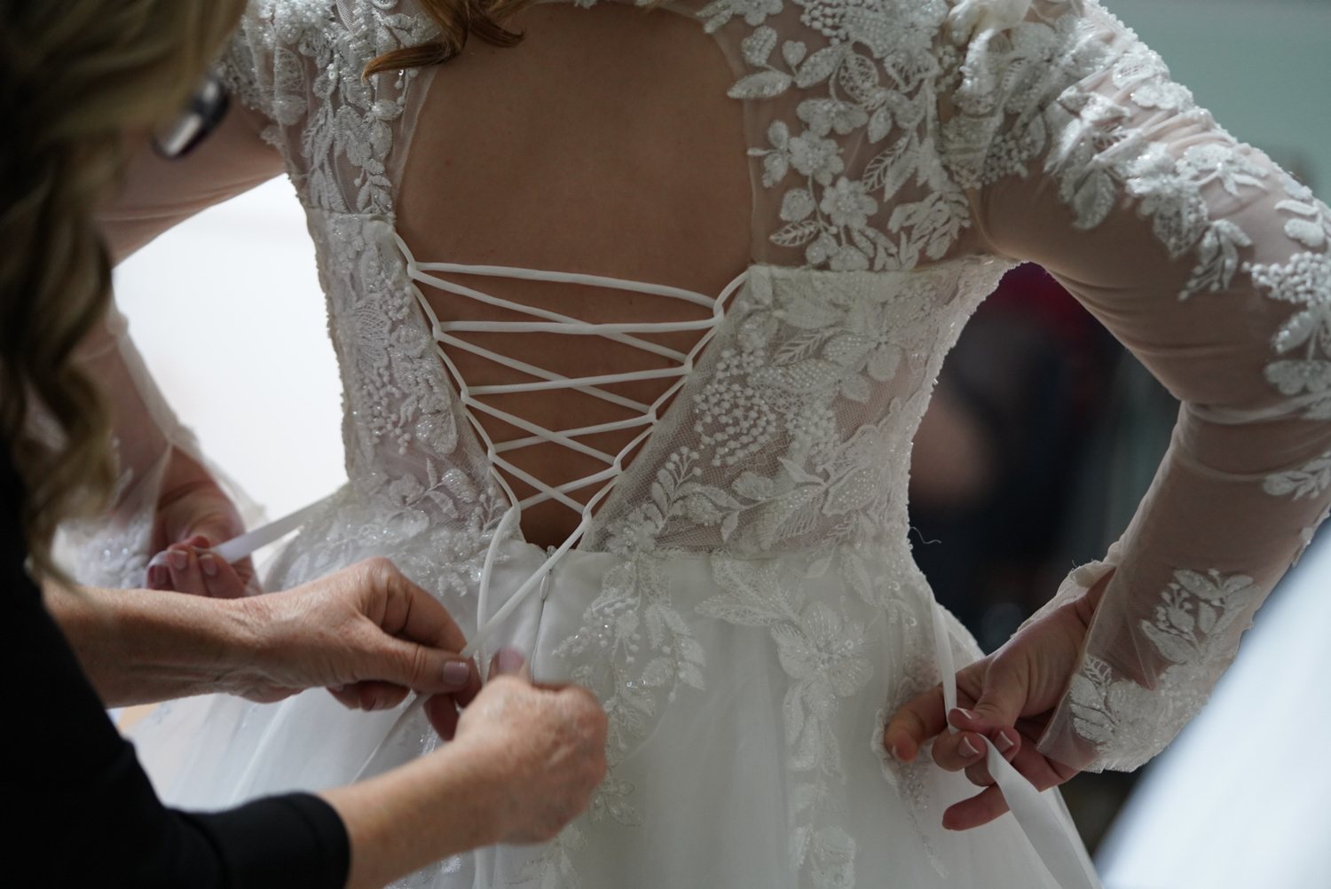 Lacing up the back of the wedding dress before a Surrey ceremony