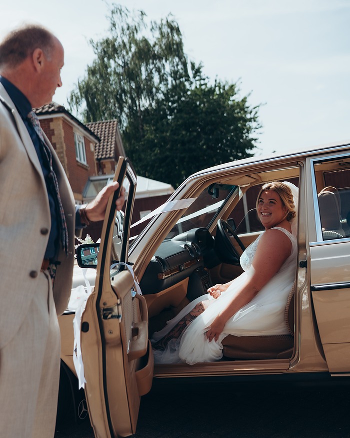 Bride stepping into a vintage wedding car