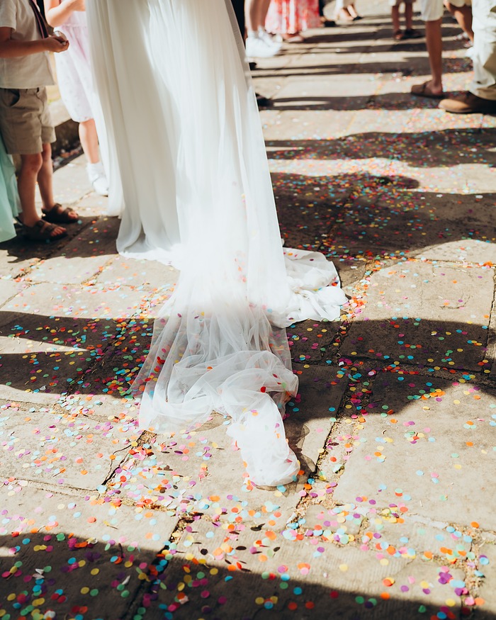 Confetti scattered around the hem of a wedding dress