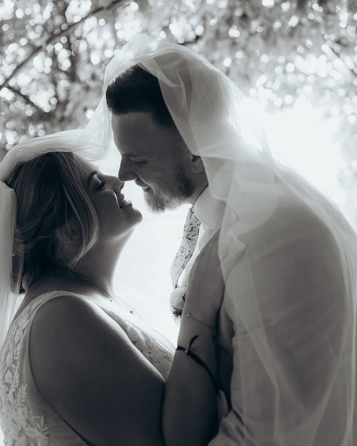 Black and white portrait of a couple under the bride's veil