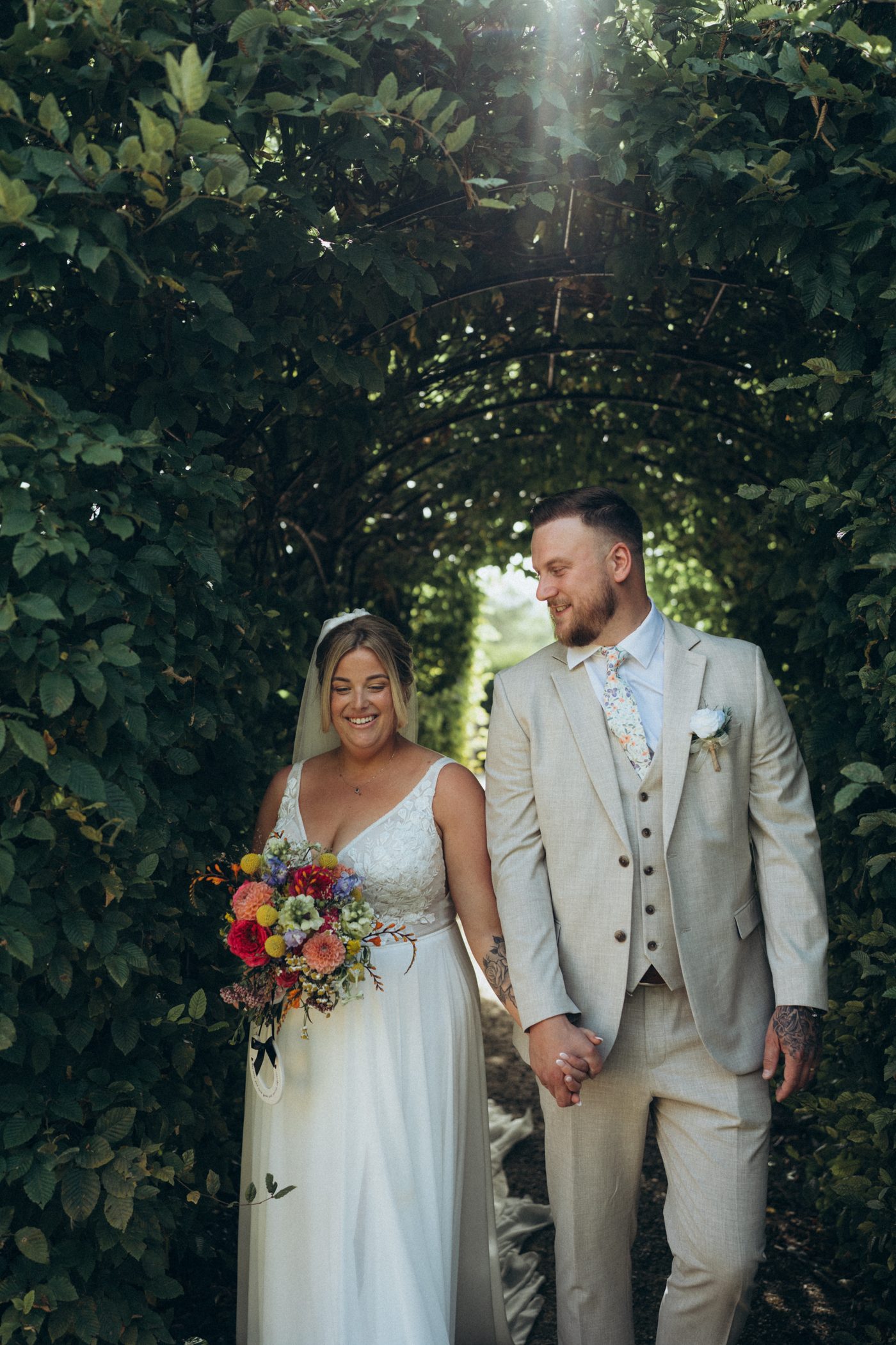 Bride and groom under a garden archway in Surrey