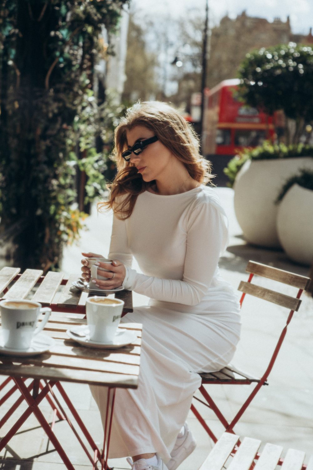 Photography session: woman in a white dress enjoying coffee at a London café